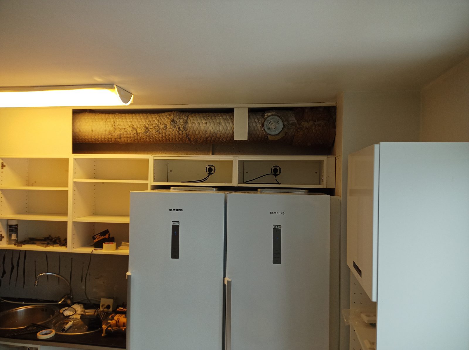 Kök under montering med synliga ventilationsrör och vitvaror på plats