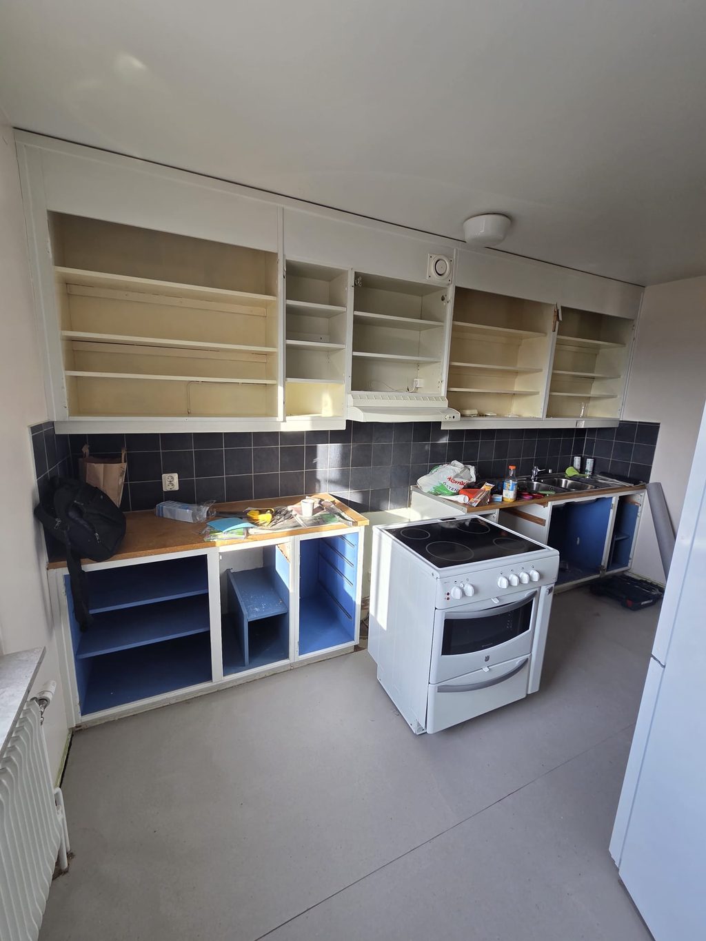 Köksrenovering med nya skåpstommar monterade utan luckor och den gamla spisen kvar